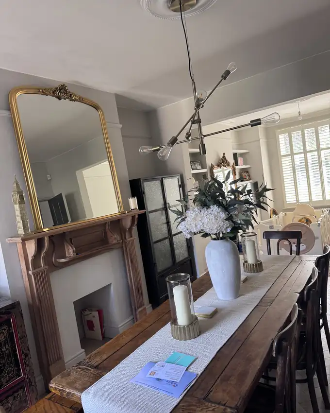 A dining room with polished mirror, dusted mantel and clean floors